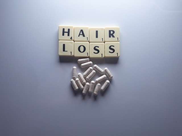 hair loss written with scrabble tiles with capsules underneath them hair transplant